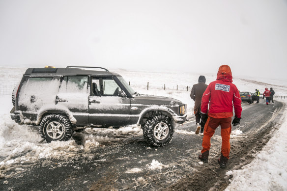 Members of a Mountain Rescue team help to clear cars from a snow drift near Ribblehead, in North Yorkshire, England, as large parts of the UK face heavy snow and freezing rain.