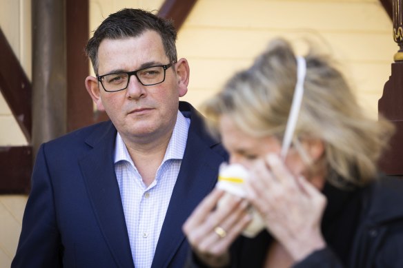 Monash Health Professor Rhonda Stuart  demonstrates how to put one of the masks on, alongside Premier Daniel Andrews on Tuesday.