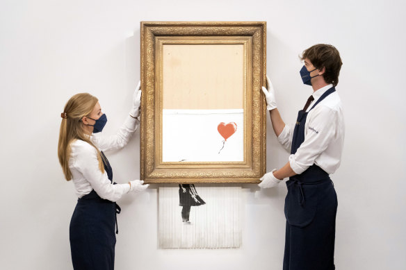 Art handlers at Sotheby’s auction house with Banksy’s Love is in the Bin before it returns to auction.