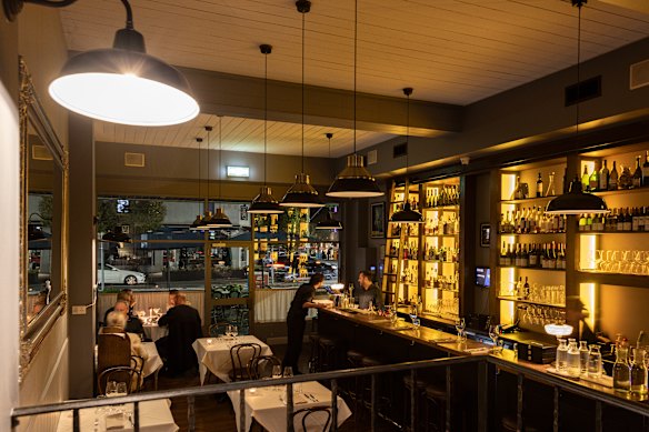 The restaurant features a bar with a library ladder to special bottles, and a mezzanine level. 
