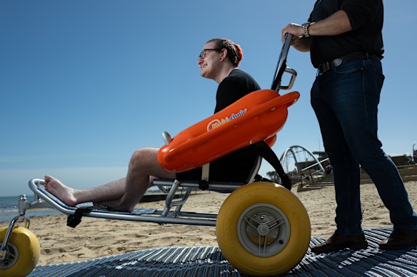Kayden Crombie is pushed by Frankston Councillor Nathan Butler at Frankston beach.