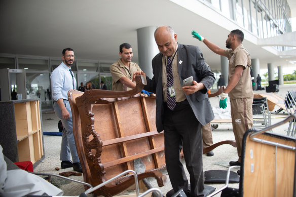 People survey damage caused by Bolsonaro supporters following a riot the previous day at Planalto Palace.