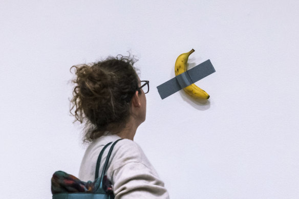 A woman looks at artist Maurizio Cattelan’s piece of art “Comedian” during an auction preview at Sotheby’s in New York.
