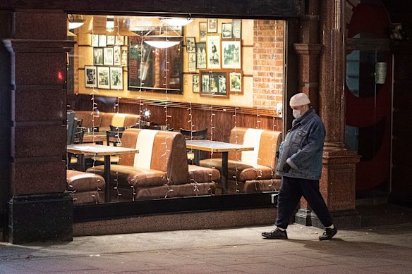 A pedestrian walks past an empty restaurant in central London. European countries are also cutting their isolation times for those infected or exposed to COVID.