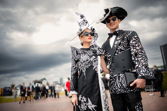 Anggie Wibowo wearing a dress made by her with batik fabric from Indonesia, Millinery from Jettah and till design and Sherlon Garbo suit by custom made Filipino young designer Chuck Morres and self made deconstructed headwear arriving at Flemington Racecourse on Derby Day, Melbourne.