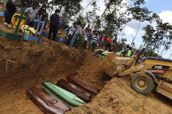 A backhoe buries coffins in a common pit at the Nossa Senhora Aparecida cemetery in Manaus.