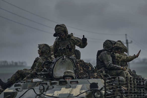 Ukrainian servicemen ride atop by an APC towards frontline positions.