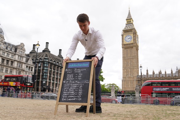 A man puts out a chalkboard with the betting odds for who will replace Boris Johnson as prime minister.