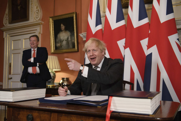 The UK's chief trade negotiator David Frost looks on as British Prime Minister Boris Johnson signs the UK-EU Brexit trade deal on Wednesday. European Commission President Ursula von der Leyen and European Council President Charles Michel signed the agreement earlier in the day in Brussels.