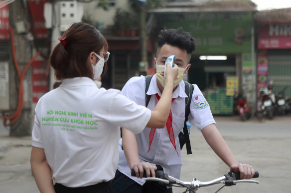 A student is scanned for temperature before entering Dinh Cong secondary school in Hanoi, Vietnam.