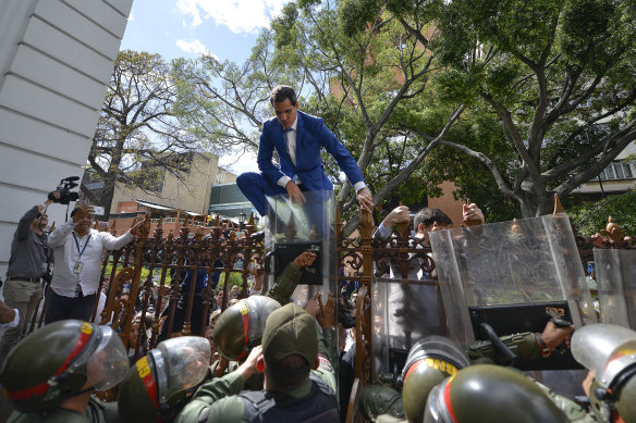 Venezuelan opposition leader Juan Guaido climbs a fence in an attempt to enter parliament.