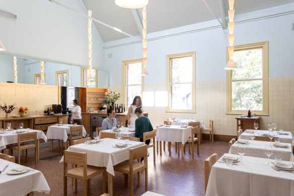 The dining room walls at Julie are tiled in cream, with pink terrazzo underfoot.