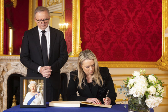 Jodie Haydon signs the co<em></em>ndolence book as her partner, Prime Minister Anthony Albanese, watches on.