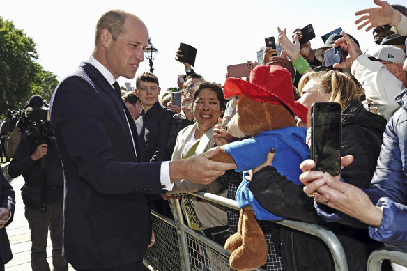 Britain’s Prince William  shakes hands with a Paddington Bear toy as he meets members of the public in the queue to view Queen Elizabeth II lying in state on September 17.