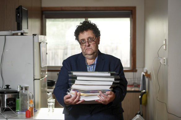 Davidh Digman in his Seaford, Melbourne home, holding his robo-debt files. 