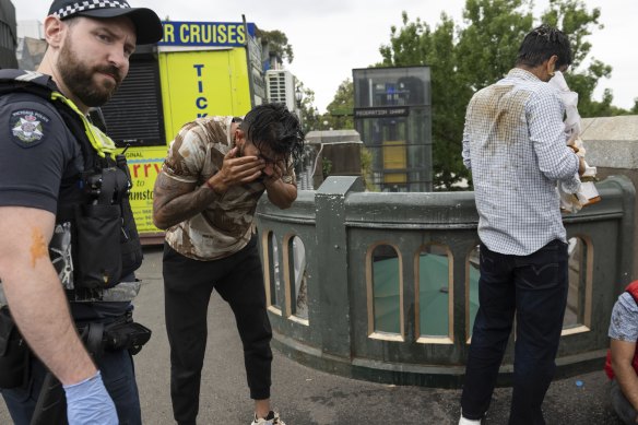 A police officer with a man who was pepper-sprayed at Federation Square.