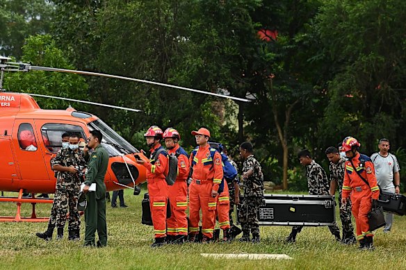 Chinese rescuers, in orange, wait to board a helicopter at a Nepalese army post in Bidur.