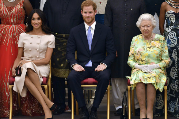 Queen Elizabeth, Prince Harry and Meghan, Duchess of Sussex pose for a group photo at the Queen’s Young Leaders Awards Ceremony at Buckingham Palace in London in 2018.