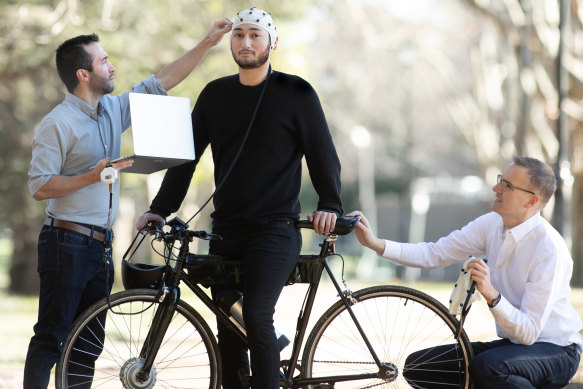 Researchers Josh Andres (left) and Floyd Mueller hook up cyclist Nathan Semertzidis to the intuitive technology.