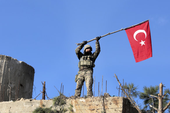 A soldier waves a Turkish flag as Turkish troops secure Bursayah hill, which separates the Kurdish-held enclave of Afrin from the Turkey-controlled town of Azaz, Syria.