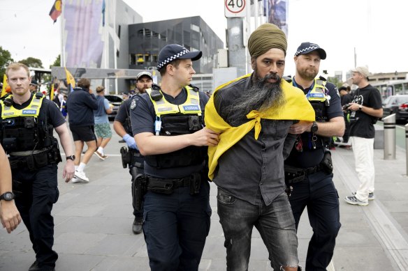 Police officers lead away a protester at Federation Square on Sunday.