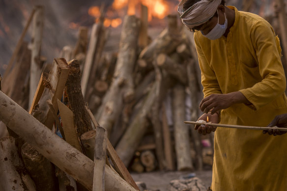 A priest lights a wooden stick as he prepares to perform the last rites of a patient who died of COVID-19 during a mass cremation in New Delhi, India. 