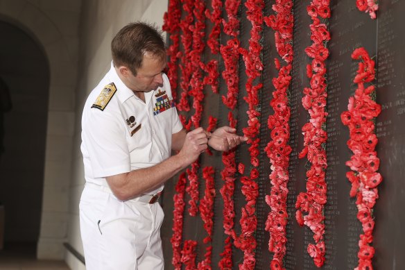 Chief of Navy Vice-Admiral Michael Noonan places a poppy next to Able Seaman Thomas Welsby Clark’s name on the Roll of Honour at the Australian War Memorial on Friday.