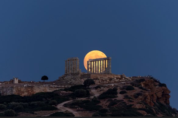 The moon rises behind the ancient marble temple of Poseidon at Cape Sounion, about 70 Km south of Athens, Greece.