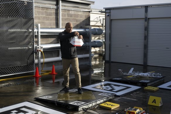 Wing Aviation Australia division operations manager Dave Ojiako-Pettit attaching food to the drone on the rooftop of Eastland shopping centre. 