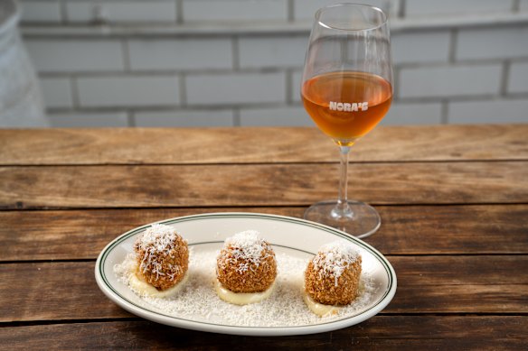 Slow-braised eggplant and mozzarella arancini alongside a glass of 2022 Leeona Orange Bianco from Tuscany.