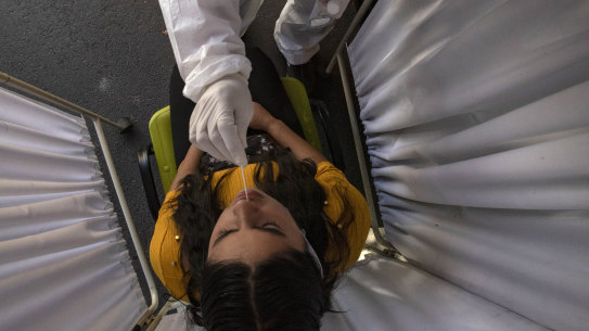 A healthcare worker is tested for coronavirus in a market in Santiago, Chile.