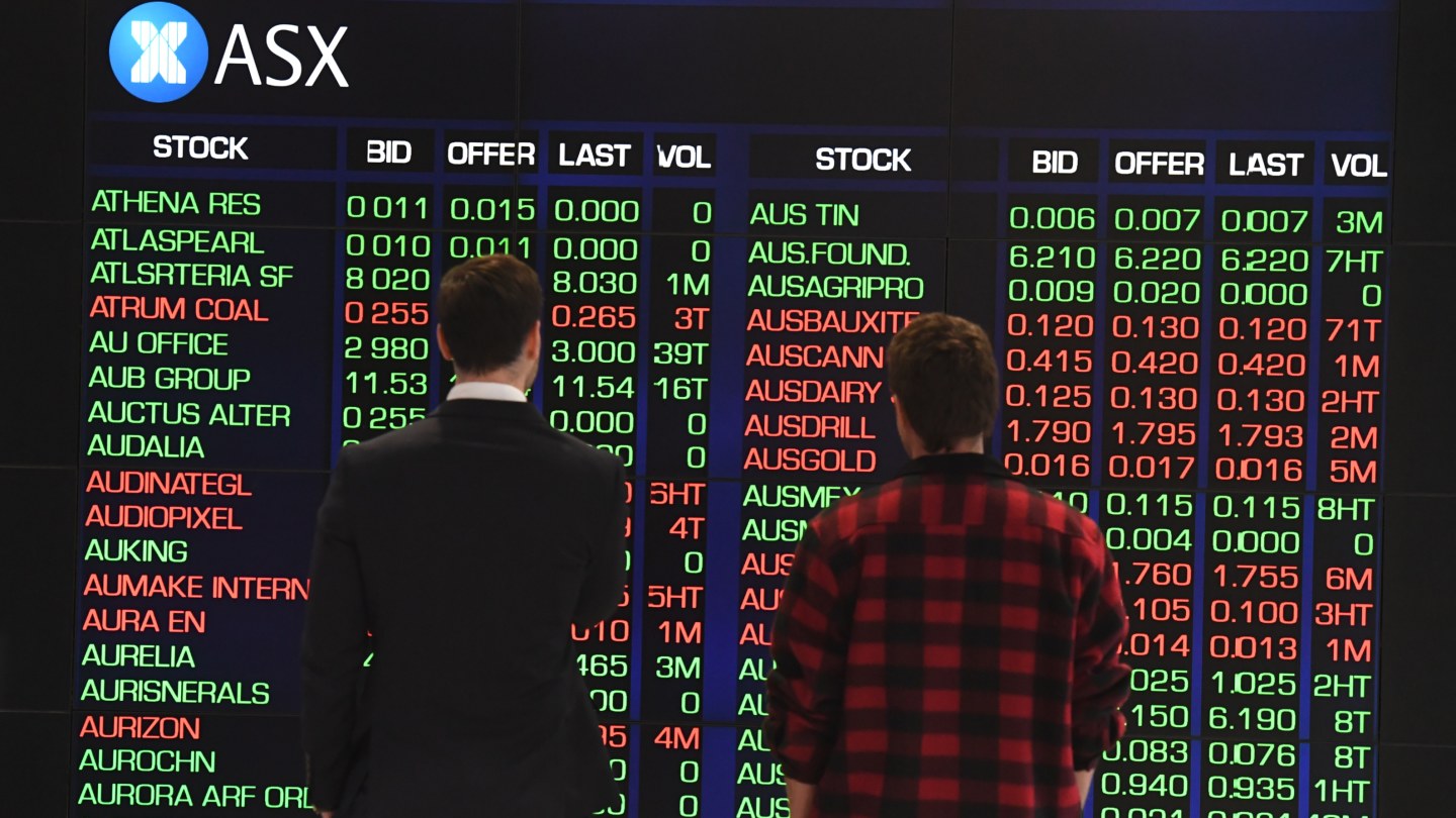 Two people looking at the ASX sharemarket boards.