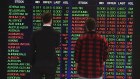 Two people looking at the ASX sharemarket boards.