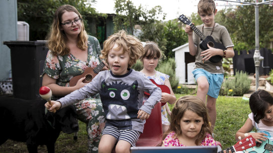 Hannah and Mark Tuton, with their chilldren, learning to play the ukulele through an online lesson.
