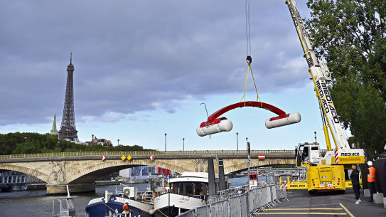 A crane is used to dismantle the starting line after the cancellation of the Open Water Swimming World Cup on the Seine in Paris.