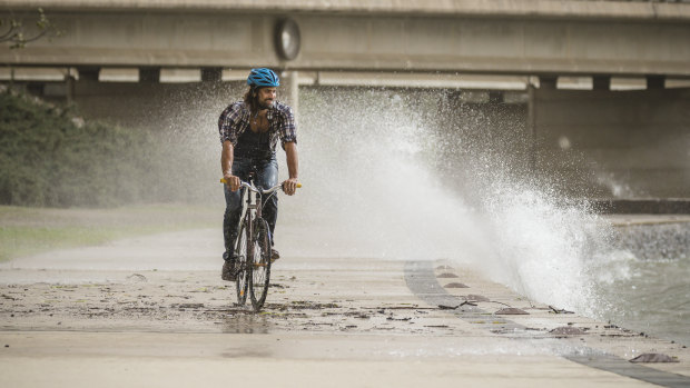 Robert Agostino from O'Connor rides home as strong winds whip up waves along the lake front in Parkes. 