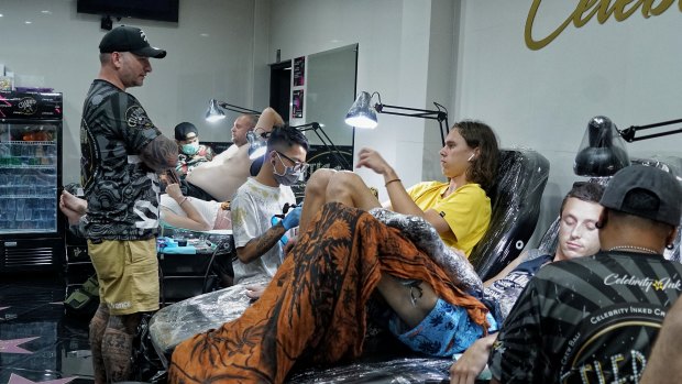 Dane Herden (left, standing) owner of Celebrity Ink Tattoo Bali studio watching his tattoo artists working.