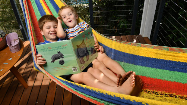 The brothers read a school book together while laying in a hammock at their home.