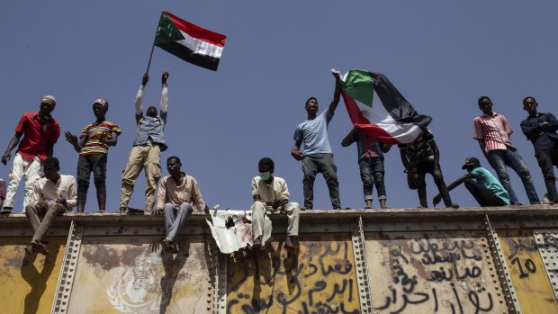 Sudanese protesters wave national flags at the sit-in outside the military headquarters in Khartoum.