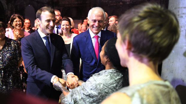 French President Emmanuel Macron, here with PM Malcolm Turnbull greeting members of Marrugeku, an indigenous Australian performance group, headed to New Caledonia on Thursday.