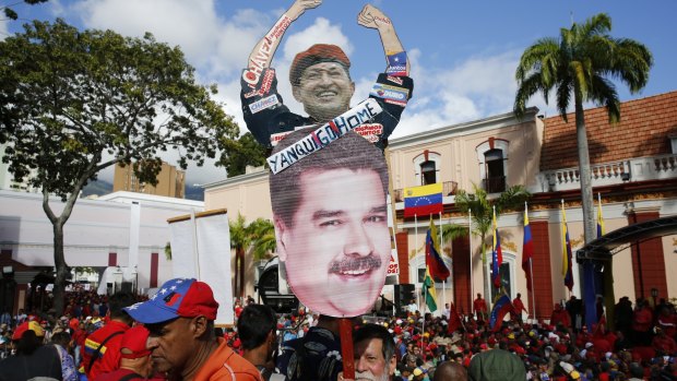 A supporter of Venezuela's President Nicolas Maduro holds a homemade poster  featuring images of Venezuela's late President Hugo Chaves and Maduro, with the message: "Yankee Go Home", during a rally outside the Miraflores presidential palace in Caracas.