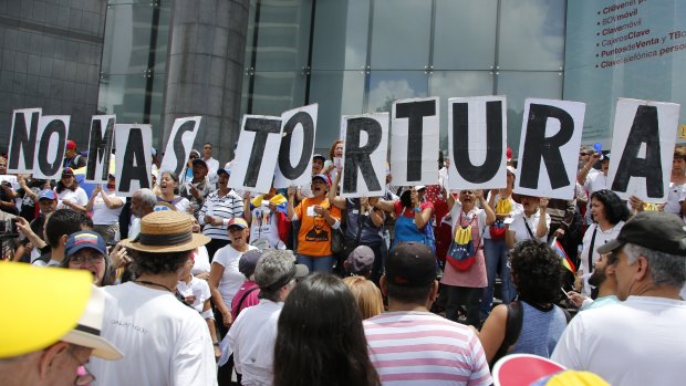 People hold placards that spell out in Spanish: "No more torture" during an opposition protest against President Nicolas Maduro in Caracas last year.