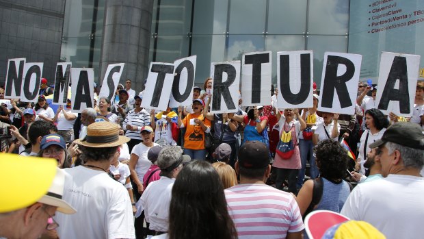 People hold placards that spell out in Spanish: "No more torture" during an opposition protest against President Nicolas Maduro in Caracas on Friday.