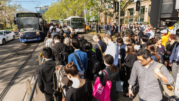Commuters waiting for tram replacement buses along St Kilda Road, near the Shrine of Remembrance.