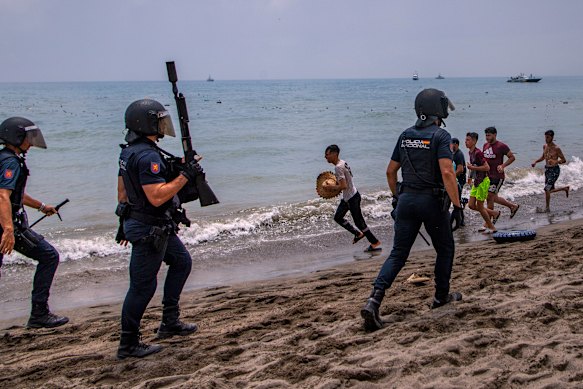 Spanish police officers respond as migrants cross from Morocco.