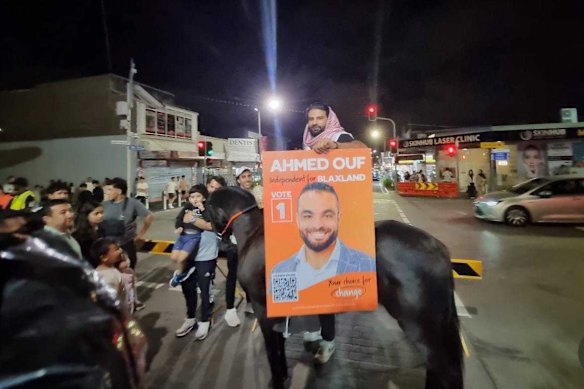A volunteer for independent Ahmed Ouf carries a poster for the candidate in Merrylands.