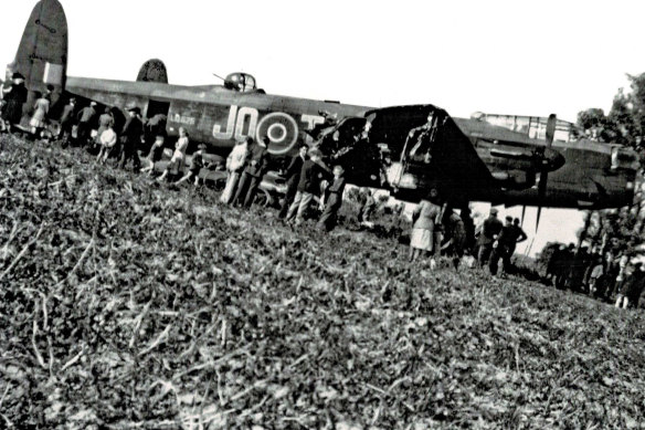 The downed Lancaster bomber surrounded by sightseers.