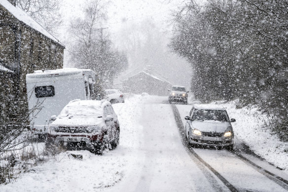 Cars drive through the snow in Gunnerside, England. Tens of thousands of people in Scotland and northern England remained without power on Sunday after a storm brought sleet, subzero temperatures and disruptions across much of the UK.