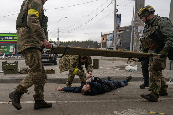 Ukrainian soldiers help a wounded man as civilians tried to flee Irpin, near Kyiv, Ukraine, on Sunday, March 6, 2022.