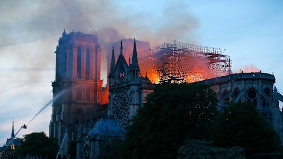 A firefighter tackles the blaze as flames and smoke rise from Notre-Dame cathedral as it burns in Paris.